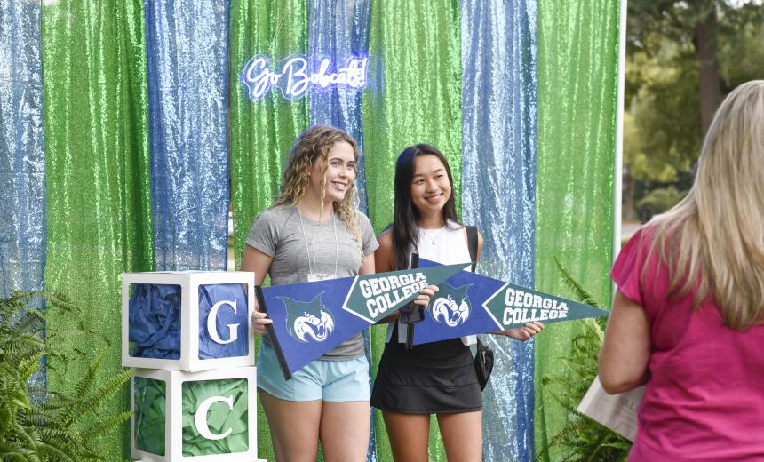 Two students pose for a photo at a GCSU themed photo booth