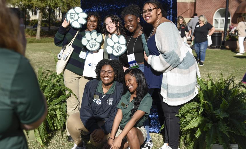 Students hold up paws at a photo booth and pose for a photo