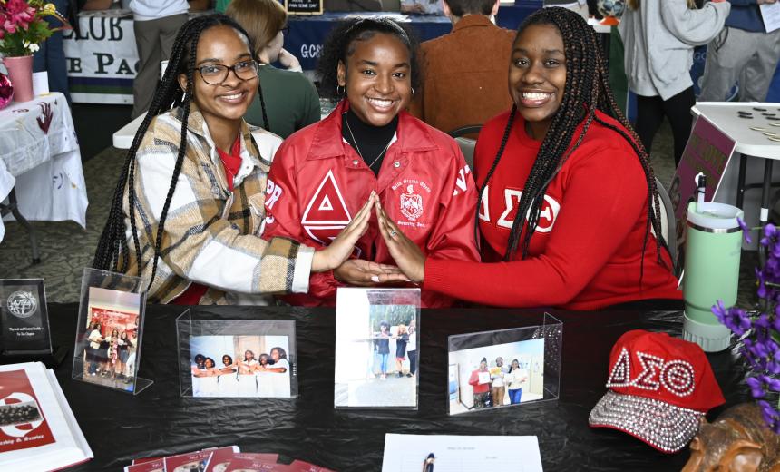 Sorority sisters smile for a photo at their booth