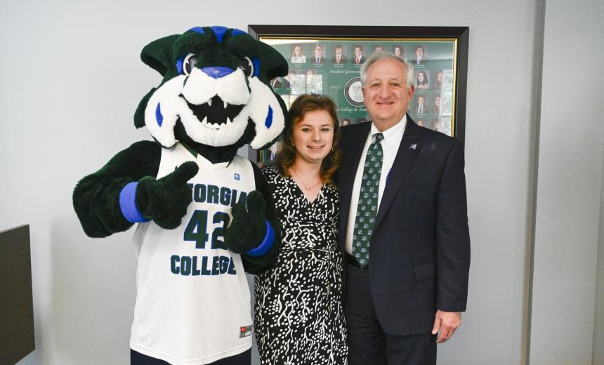 Three individuals - Thunder, Georgia College's bobcat mascot, in a jersey, Axel, a young woman with brown hair wearing a dress, and Dan Nadler, an older man in a suit. 