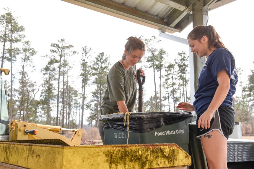 Two students process compost
